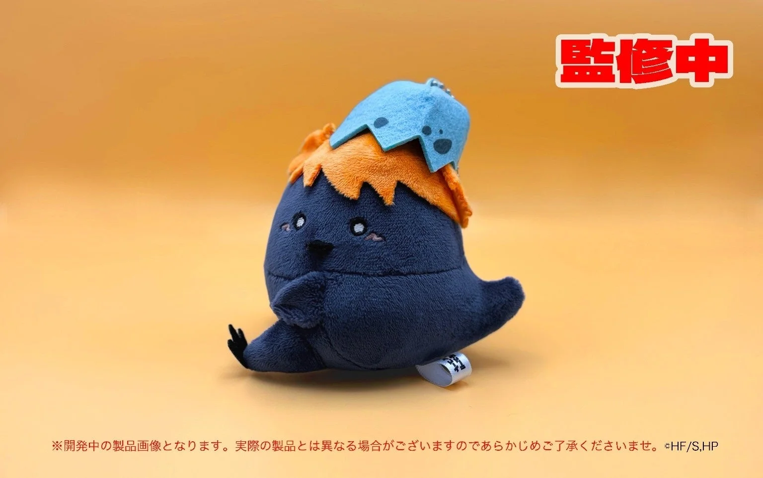 紺色の体にオレンジ色の髪、水色の帽子をかぶったキャラクターのぬいぐるみ